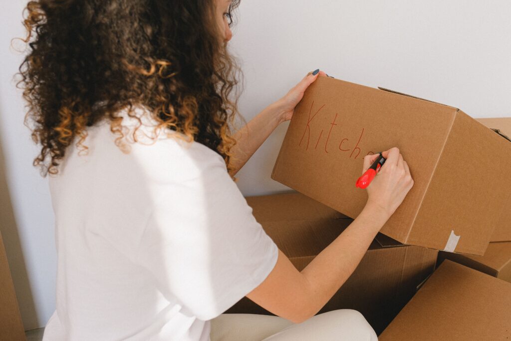 Een vrouw schrijft een label op een doos